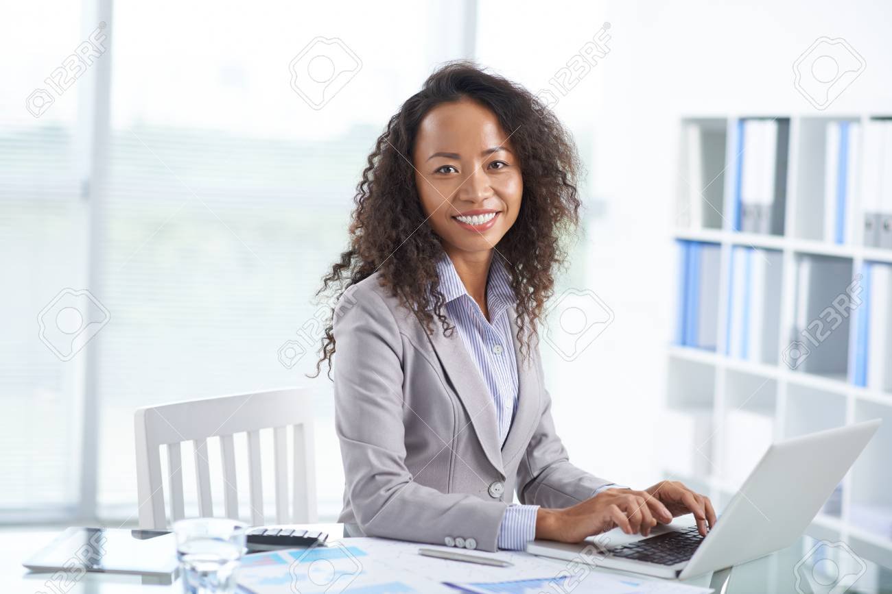 Portrait of cheerful Asian office manager working on laptop